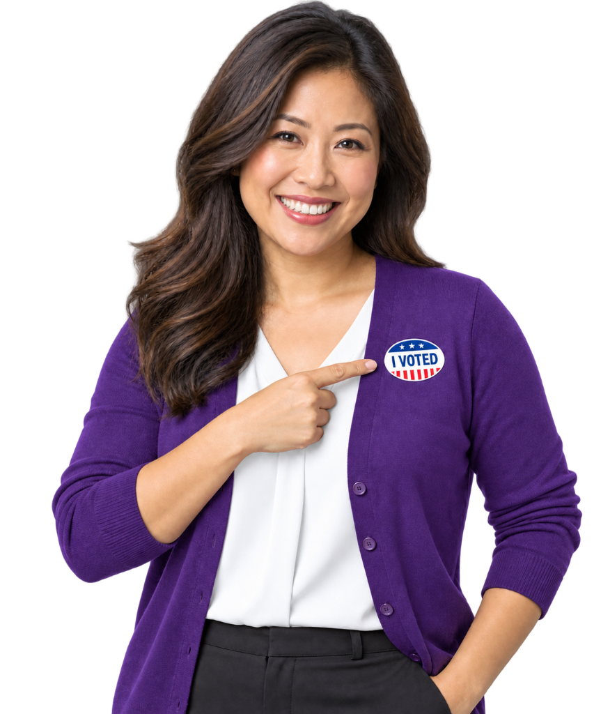 A smiling mom pointing to her I Voted sticker